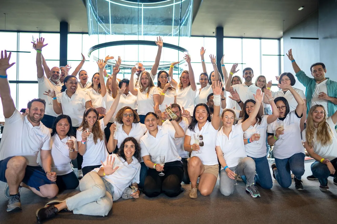 Grand groupe d'entreprise en t-shirts blancs, bras levés, autour de la soufflerie