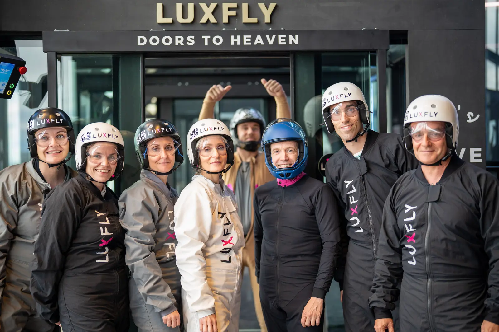 Une équipe en combinaisons de vol et casques devant l'entrée de LUXFLY